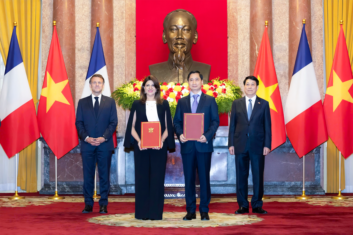 Ông Ngô Chí Dũng, Tổng Giám đốc kiêm Chủ tịch HĐQT Công ty Vắc xin Việt Nam (VNVC) và bà Zainab Sadat Qayyum, Chủ tịch Sanofi Đông Nam Á - Ấn Độ trao văn kiện thỏa thuận hợp tác chuyển giao công nghệ sản xuất vắc xin của Sanofi tại Nhà máy Vắc xin và Sinh phẩm VNVC trước sự chứng kiến của Chủ tịch nước Lương Cường và Tổng thống Pháp Emmanuel Macron.