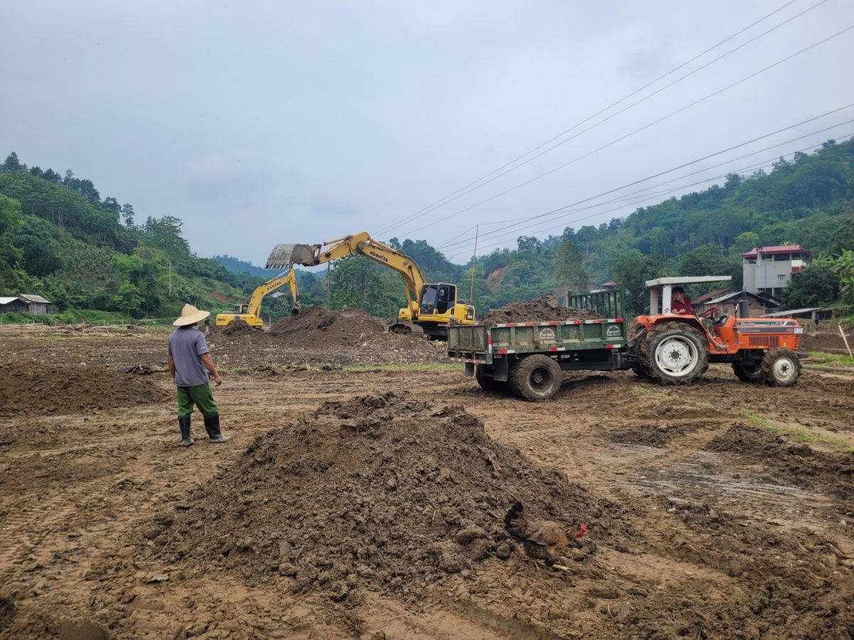 Máy xúc lấy đất màu trải lên mặt ruộng.