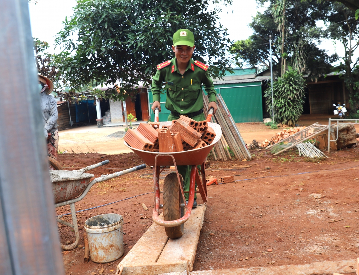 Một đồng chí công an xã biên giới Quảng Trực, huyện Tuy Đức, tỉnh Đắk Nông tham gia vận chuyển gạch hỗ trợ xây nhà cho người dân.