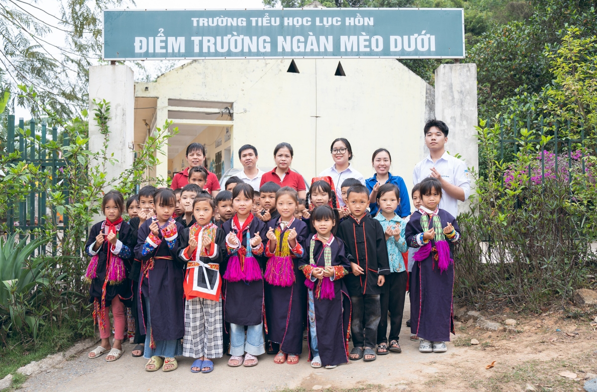 Phan Thị Thanh Trà (áo trắng hàng sau) dùng các thành viên dự án và các em học sinh điểm trường Ngàn Mèo Dưới trong buổi trao tặng Tủ sách hy vọng