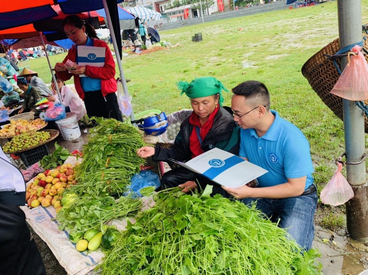 Nhân viên BHXH tư vấn chính sách BHXH tới người dân buôn bán nhỏ lẻ tại các khu chợ