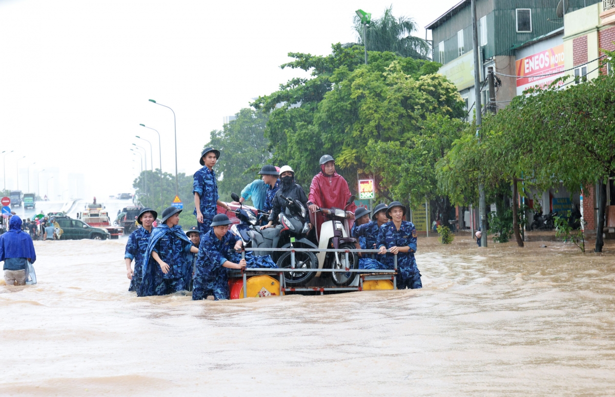 Các cán bộ chiến sĩ nỗ lực đưa người dân qua điểm ngập lụt