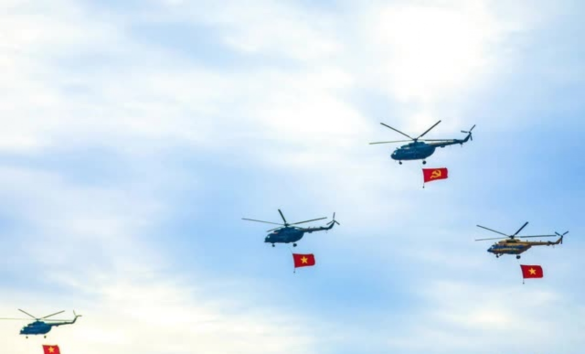 Đội hình trực thăng bay qua quảng trường Ba Đình theo đội hình 1-3-3-3, giãn cách 100m. Chiếc trực thăng dẫn đầu treo cờ Đảng, các trực thăng phía sau treo Quốc kỳ. Lá cờ có diện tích 20m² (dài 5,4m, rộng 3,6m) tung bay trên bầu trời Hà Nội sáng 2-9 - Ảnh: DANH KHANG