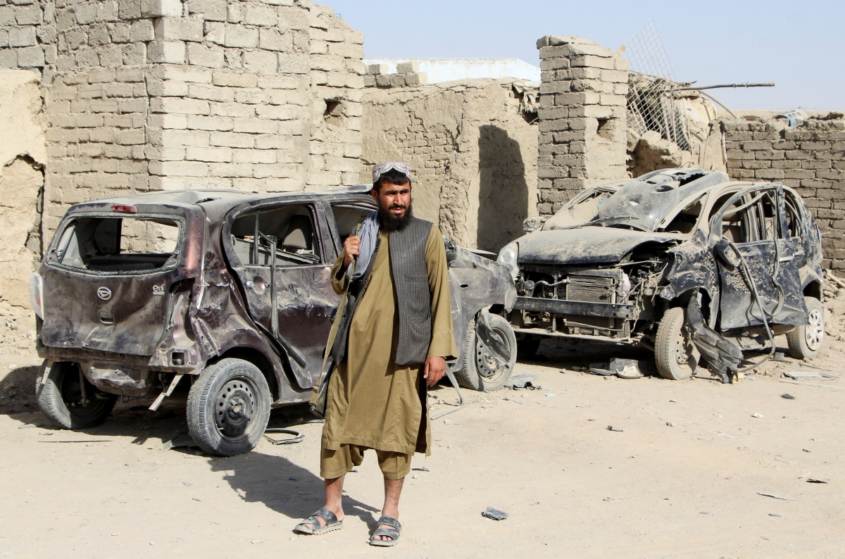 Một tay súng của Taliban đứng cạnh một chiếc ô tô bị phá hủy do cuộc không kích của quân đội Pakistan nhằm vào thị trấn Spin Boldak, tỉnh Kandahar, Afghanistan ngày 16/10 (Reuters)