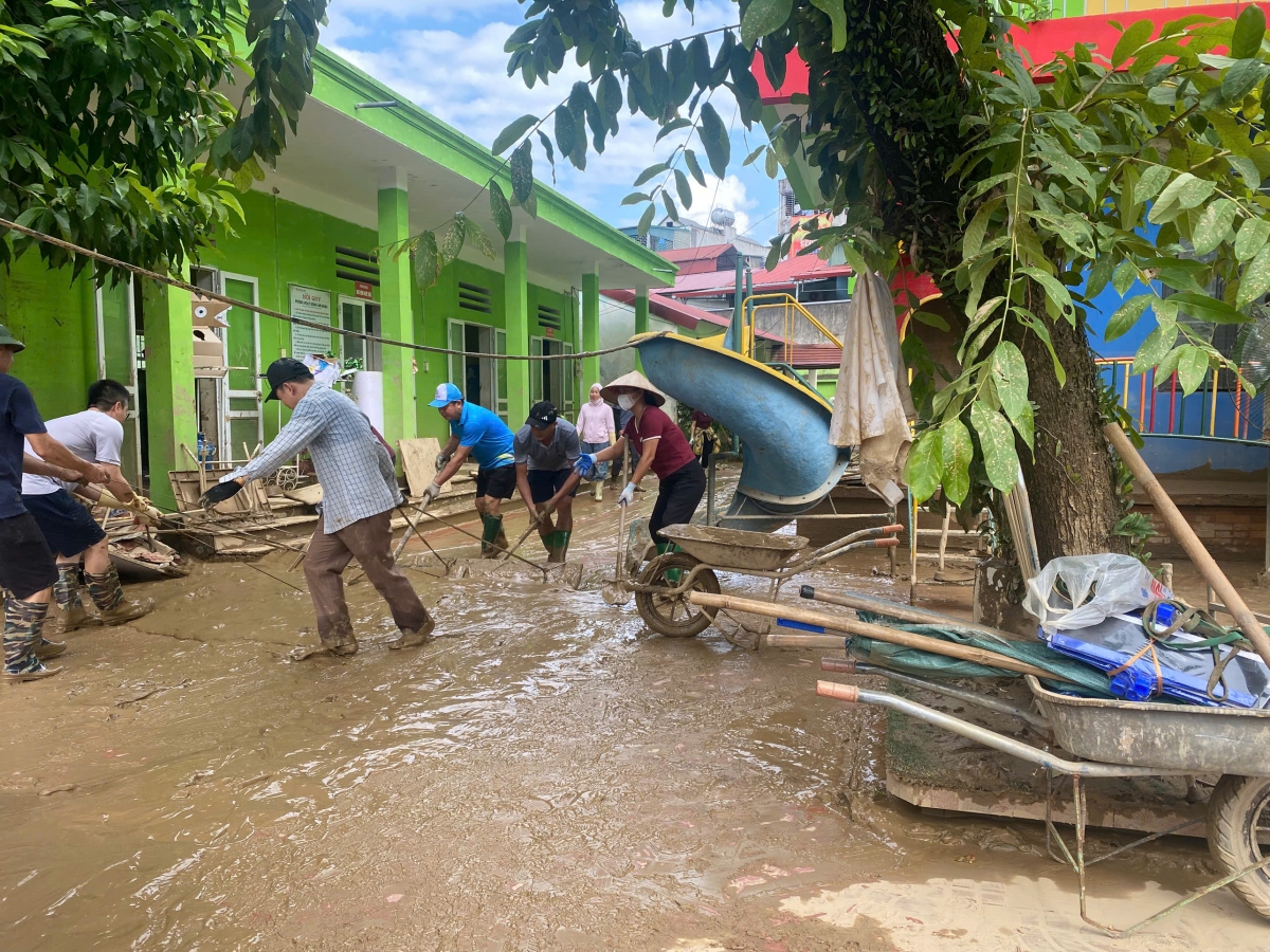 Các lực lượng cùng tham gia dọn bùn đất tại sân trường sau lũ