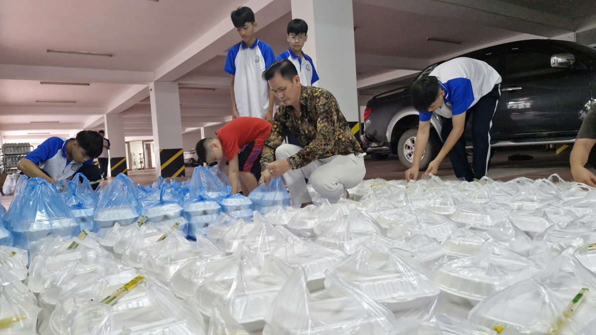 Anh Nguyễn Hưng Thịnh cùng các em học sinh đóng gói các xuất cơm để mang tới người dân bị ngập lụt