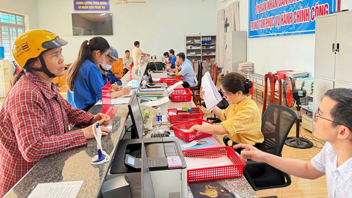 Cán bộ xã hướng dẫn người dân làm thủ tục.