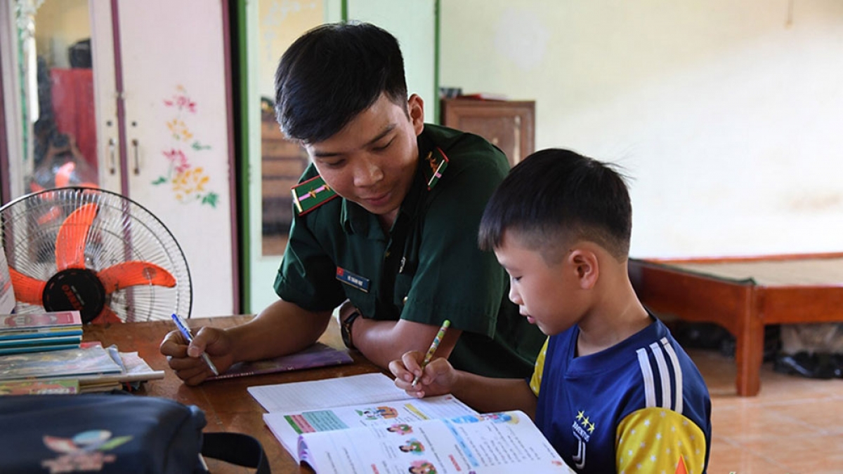 Chiến sĩ bộ đội biên phòng dạy học cho con nuôi của đồn (ảnh: QĐ)