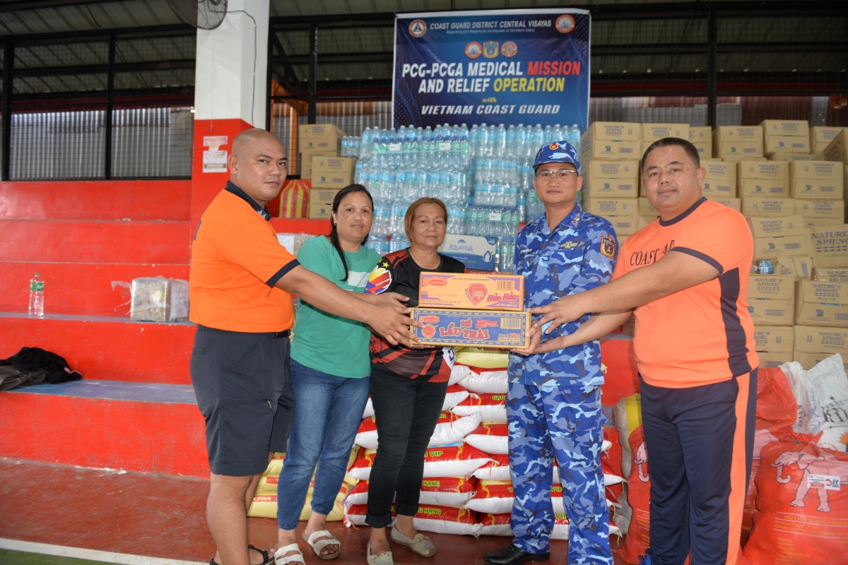 Cán bộ đoàn công tác Cảnh sát biển Việt Nam và lãnh đạo Khu vực Trung tâm Visayas, Lực lượng bảo vệ bờ biển Philippines bàn giao gạo cùng các nhu yếu phẩm cho đại diện chính quyền tỉnh Bogo, Philippines.