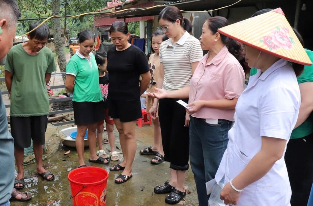 Nhân viên y tế hướng dẫn người dân khử trùng nguồn nước bằng Cloramin B