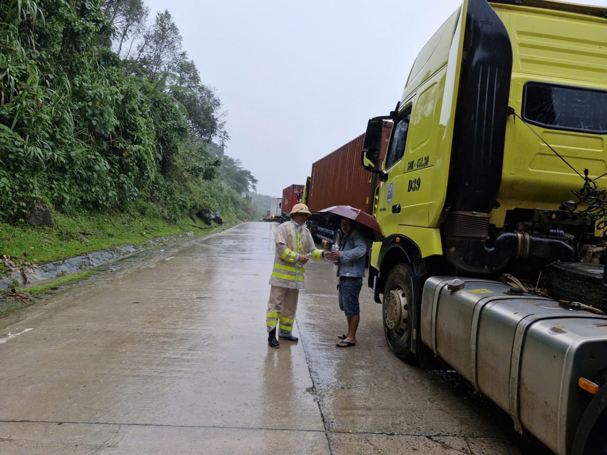Lực lượng Cảnh sát Giao thông Công an tỉnh Quảng Ngãi tiếp tế cho các lái xe bị cô lập giữa 2 điểm sạt lở đèo Lò Xo, đường Hồ Chí Minh.