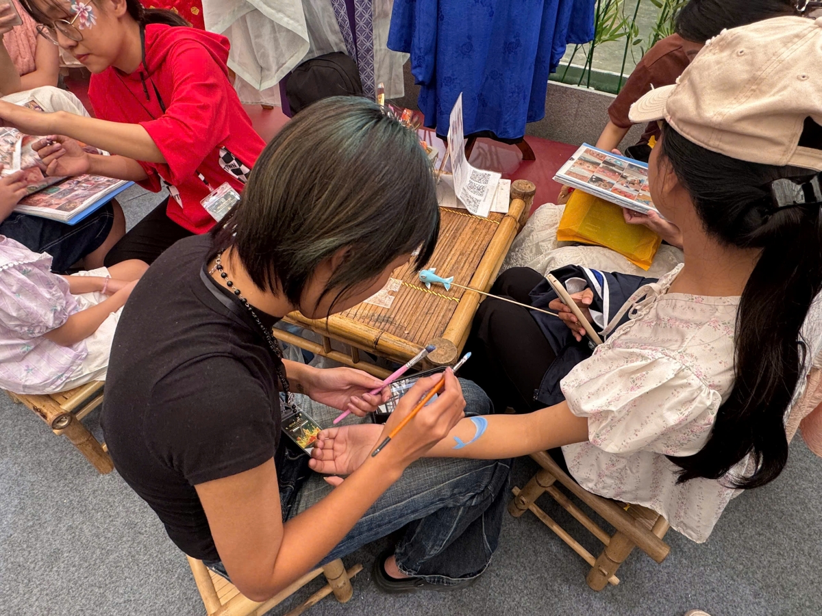 Các bạn trẻ và trẻ em hào hứng trải nghiệm vẽ lên cơ thể tại khu vực trưng bày nghệ thuật truyền thống