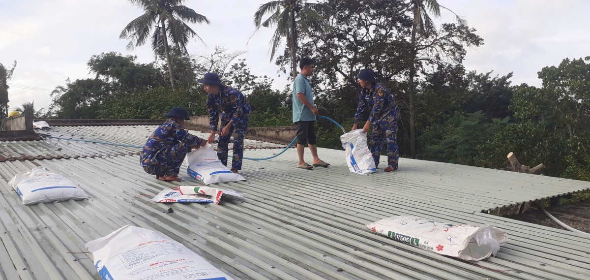 Cán bộ chiến sĩ Trạm 555, Trung đoàn 351 giúp đỡ nhân dân xã Đề Gi, tỉnh Gia Lai gia cố mái tôn, chằng chống nhà cửa.