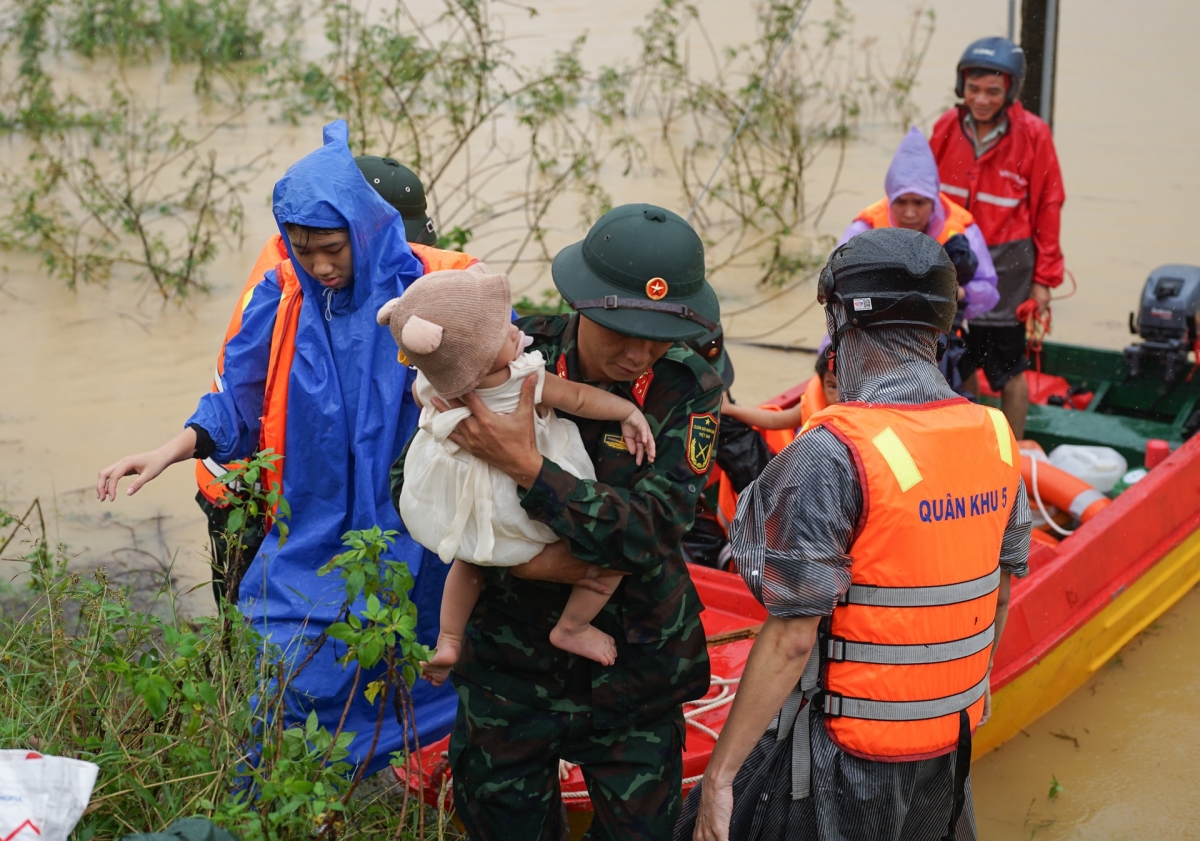 Bộ đội hỗ trợ đưa một trẻ nhỏ ra khỏi vùng ngập lụt.