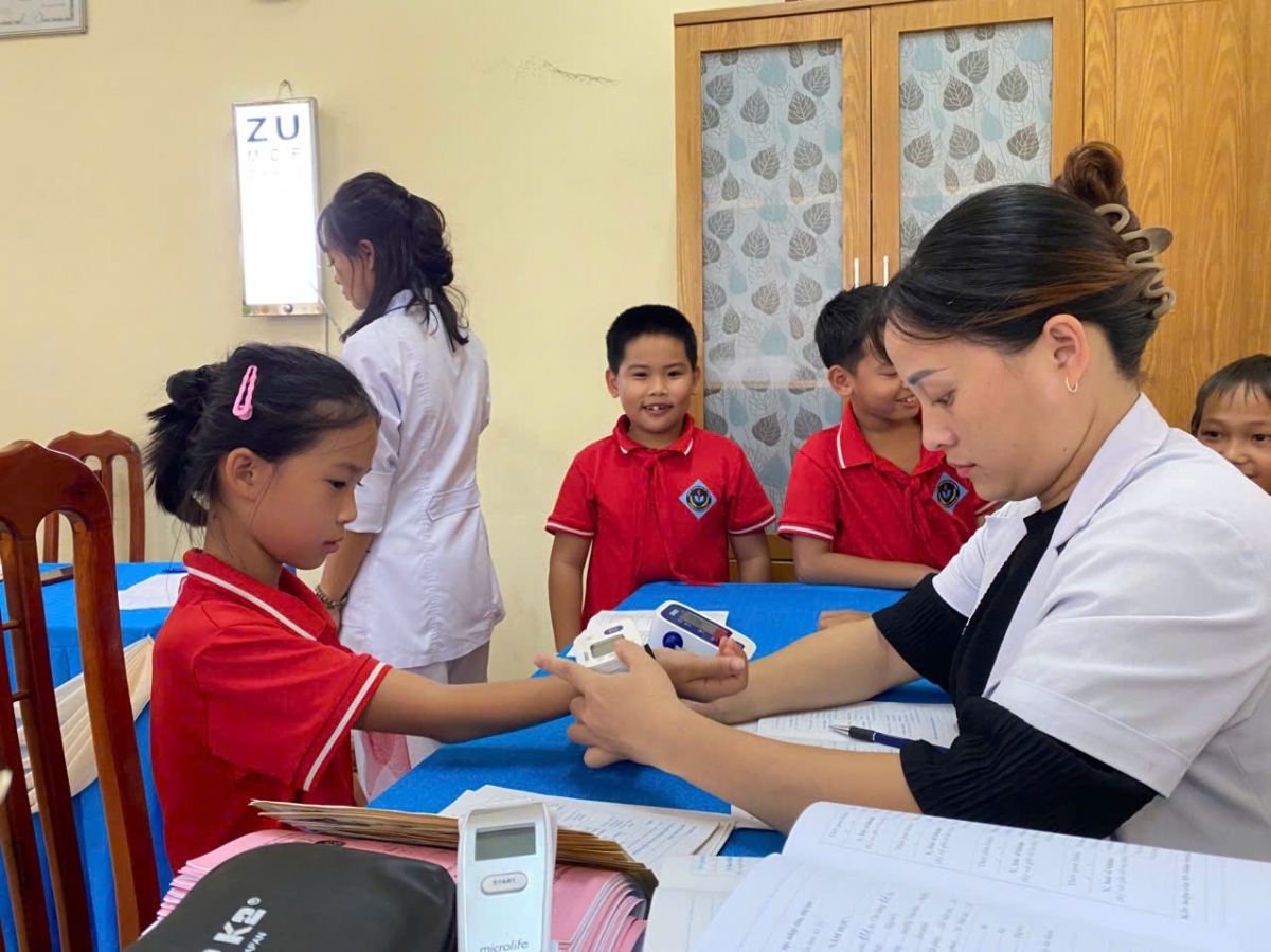 Nhân viên y tế tại Quảng Ninh kiểm tra sức khoẻ trước khi tiêm phòng cho trẻ