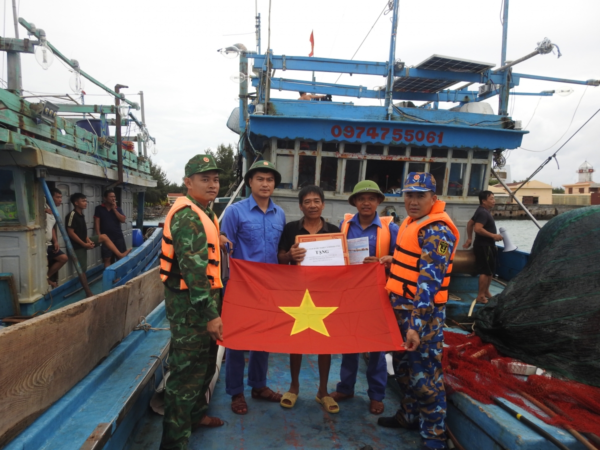 Cán bộ, chiến sĩ đảo Đá Tây thăm hỏi tặng cờ cho ngư dân vào tránh trú bão