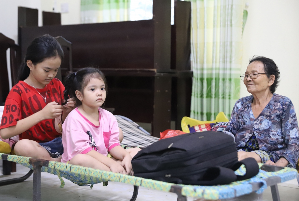 Hai cháu nhỏ cùng bà ngoại tránh trú bão tại trụ sở UBND phường Xuân Đài. Chị lớn tranh thủ tết tóc cho em.