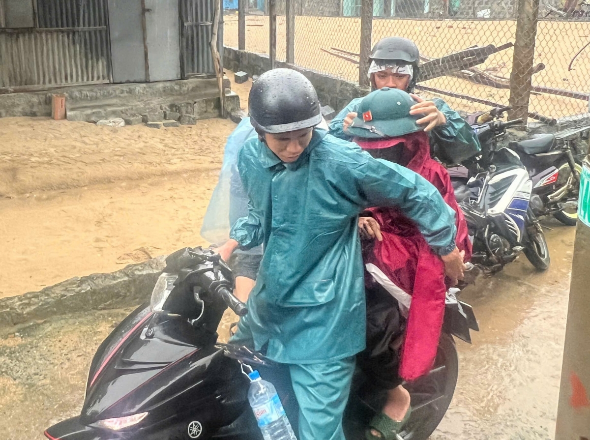 Lực lượng chức năng hỗ trợ một cháu nhỏ ở phường Sông Cầu đến nơi tránh trú bão.