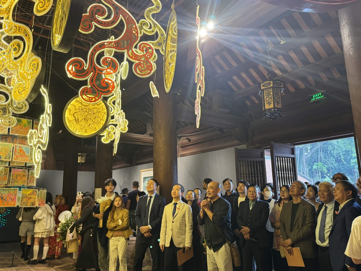 Hoạ sỹ Vũ Xuân Đông (cầm míc) giới thiệu các tác phẩm với đại biểu và du khách tham quan