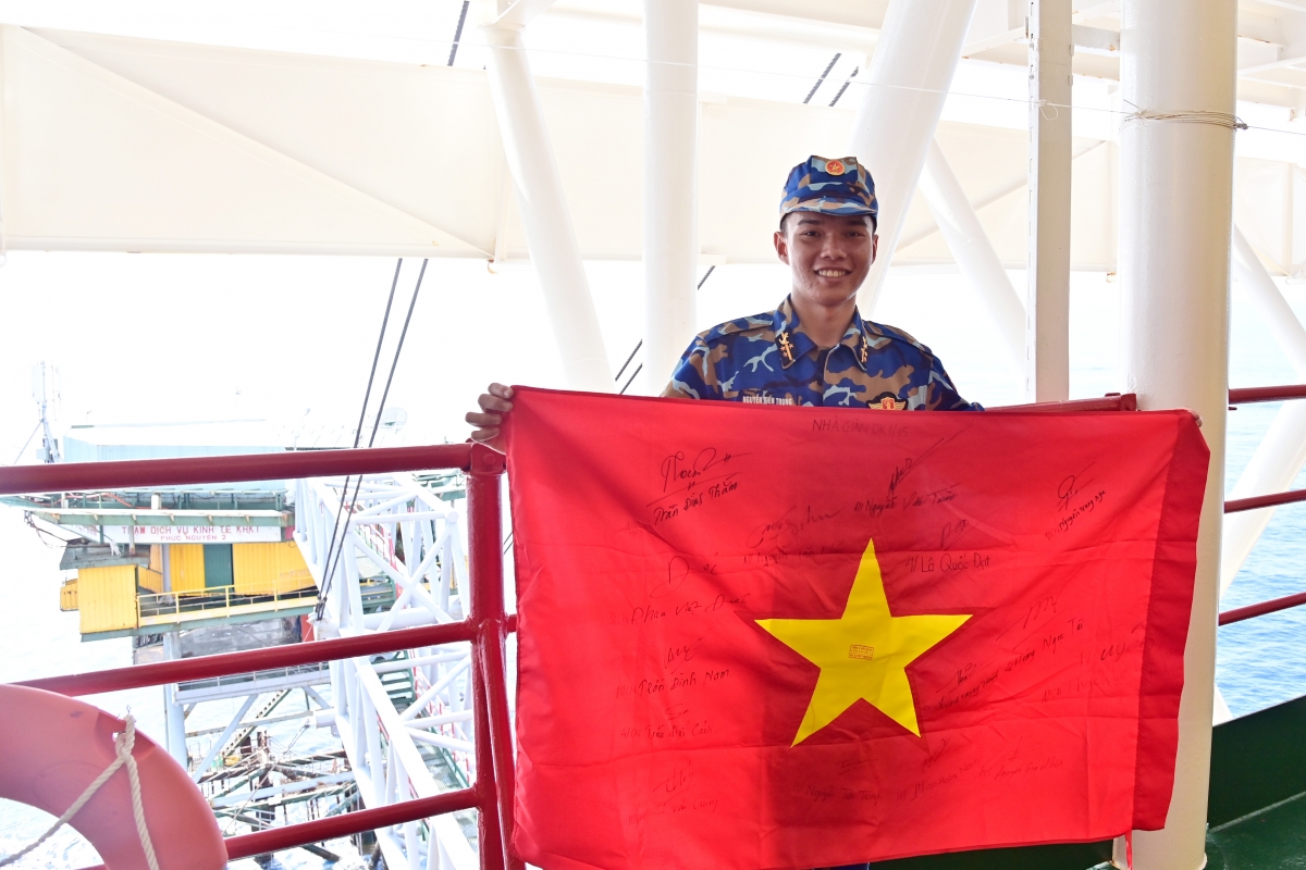 Hoàn thành công tác tại Nhà giàn DK1/15, Thượng sĩ Nguyễn Tiến Trung, mang theo lá cờ Tổ quốc, có chữ ký của cán bộ, chiến sĩ nhà giàn gửi tặng làm kỷ niệm