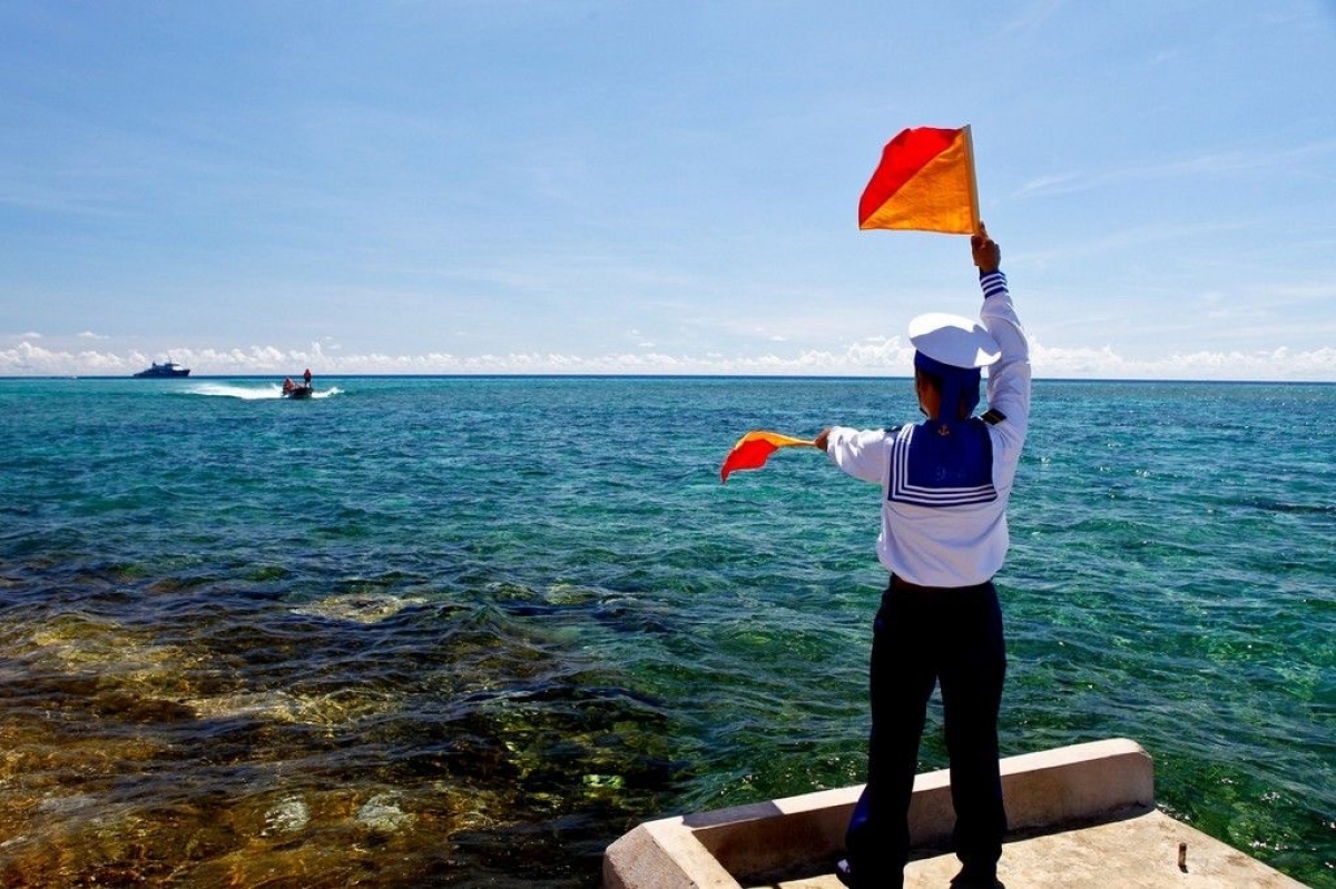 Chiến sĩ thông tin sử dụng tín hiệu cờ tay để hướng dẫn xuồng vào đảo