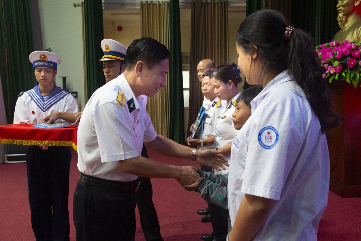 Đại tá Đỗ Hồng Duyên trao qua cho 2 cháu là con ngư dân do Vùng 2 nhận đỡ đầu và các gia đình chính sách các đơn vị của Vùng 2 Hải quân