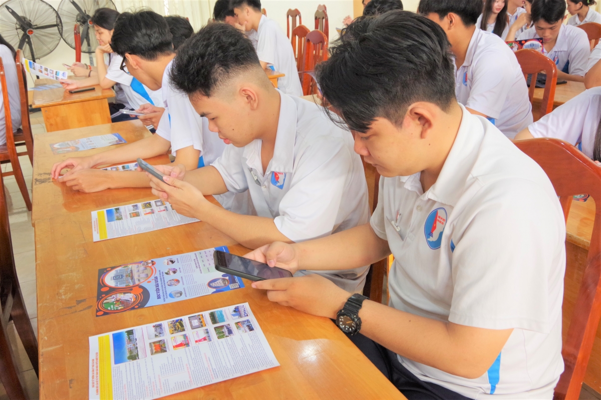 Học sinh sử dụng điện thoại thông minh quét mã QR trên tờ rơi tuyển sinh, để tra cứu các nôi dung tuyển sinh vào Học viện Hải quân năm 2026