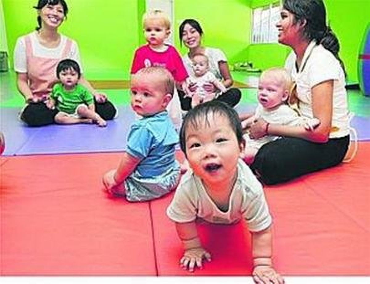 Trẻ nhỏ và các cô bảo mẫu tại trung tâm Babies Inc - Ảnh: Straits Times