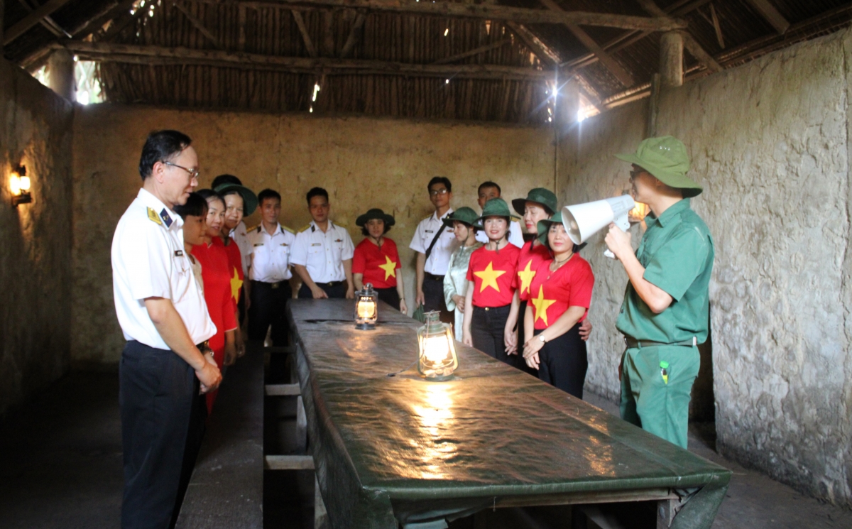 Đoàn công tác tham quan, nghe hướng dẫn viên giới thiệu tại địa đạo