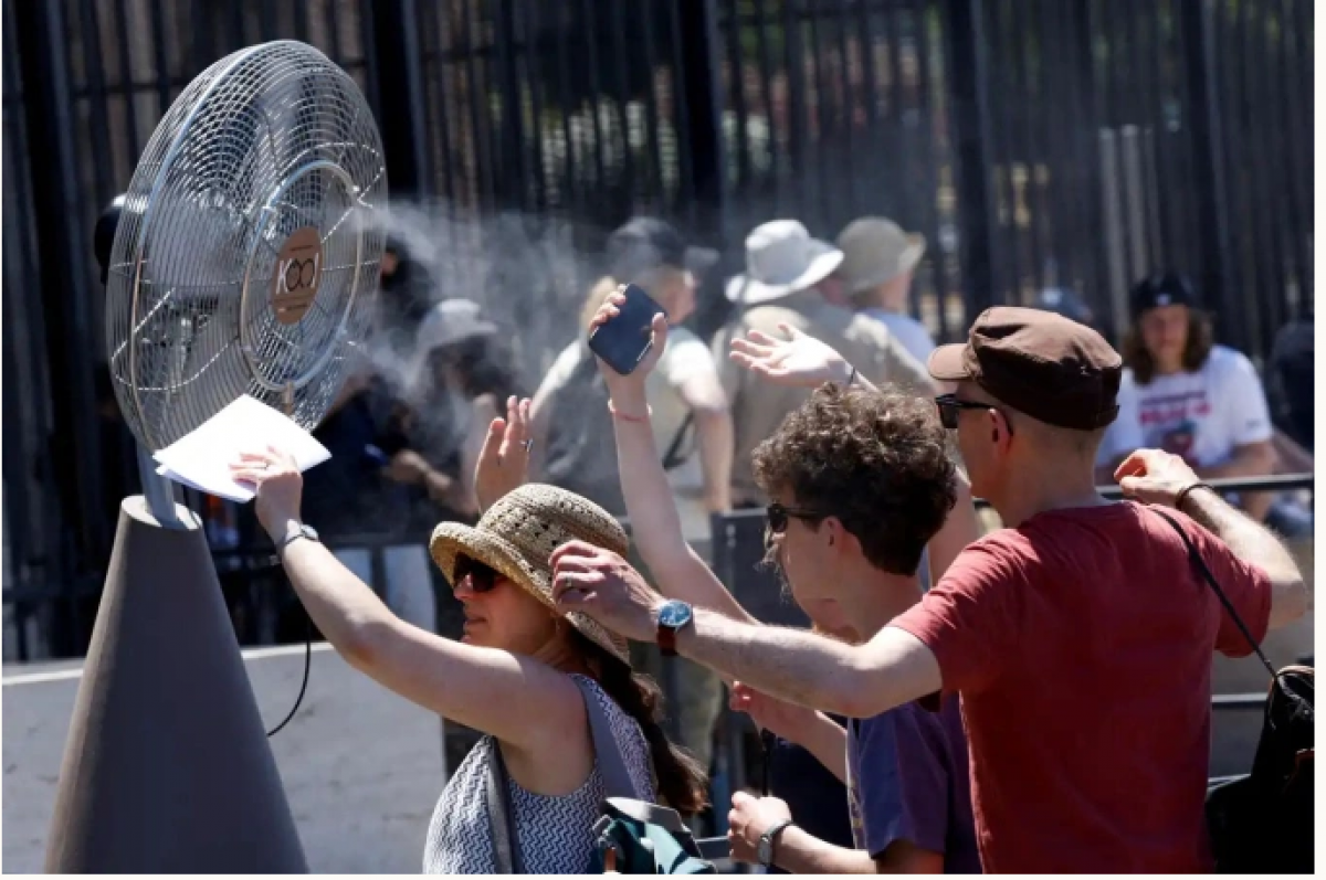 Người dân giải nhiệt trước quạt phun sương ở Rome, Italy. Ảnh: Reuters