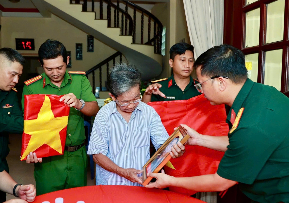 Ông Phan Văn Tư - con trai của Mẹ Việt Nam Anh hùng Huỳnh Thị Tui đón nhận di ảnh của 2 anh trai. (Ảnh: BTL TP.HCM)