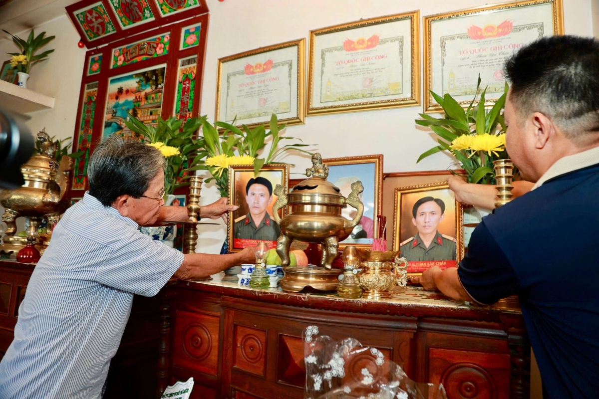Ông Phan Văn Tư trân trọng đặt di ảnh của 2 anh trai là liệt sĩ Phan Văn Ngọc và liệt sĩ Phan Văn Châu lên bàn thờ. (Ảnh: BTL TP.HCM)