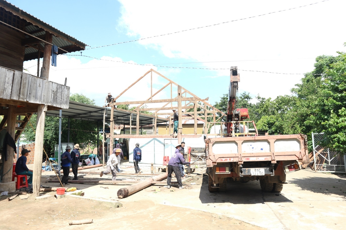 Lực lượng hỗ trợ người dân buôn Jứ tháo dỡ, di chuyển khung nhà sàn đến nơi ở mới.