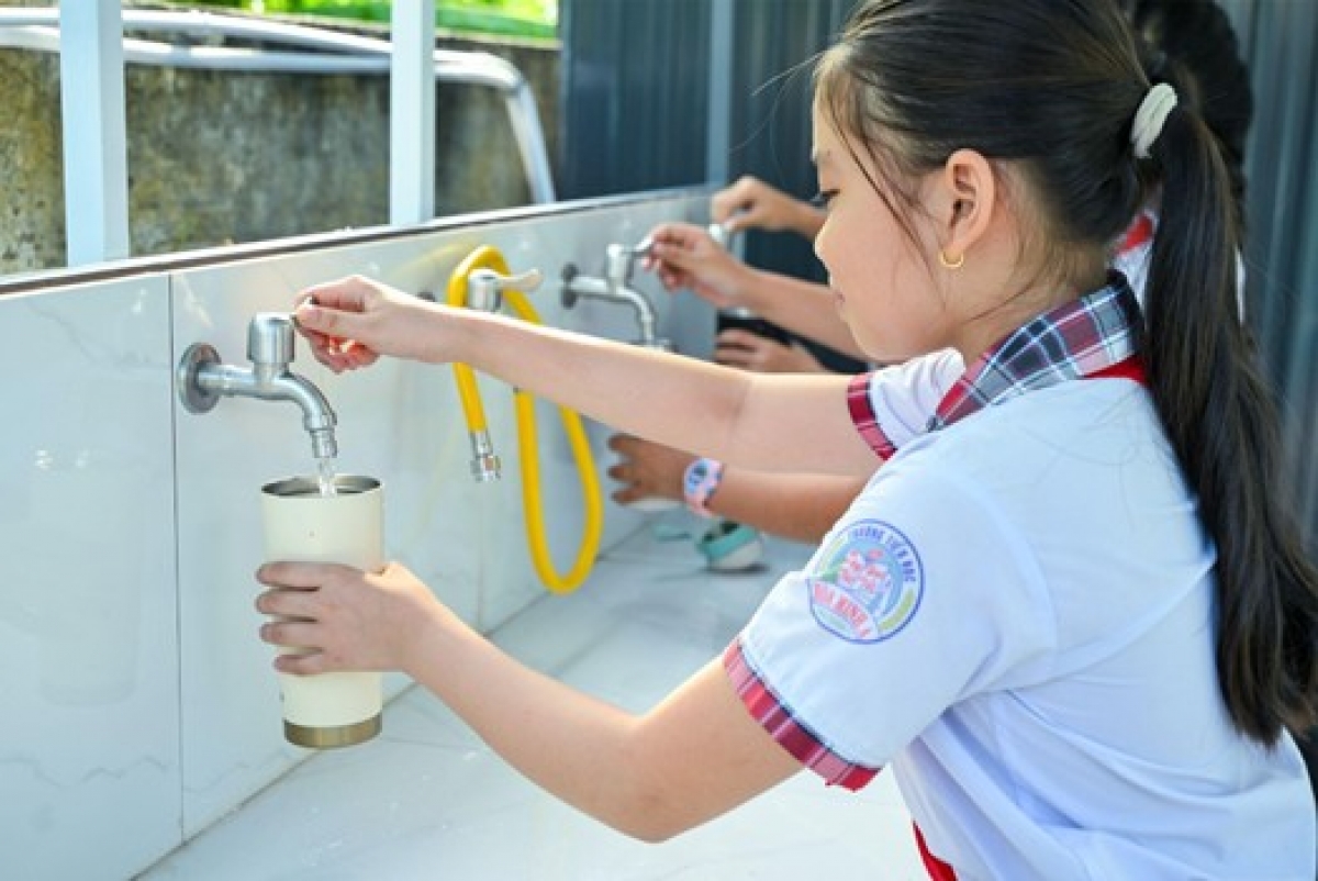 Các em học sinh tại trường Tiểu học Hòa Minh (tỉnh Vĩnh Long) sử dụng nước sạch từ hệ thống thu trữ, lọc nước uống do UNIQLO trao tặng