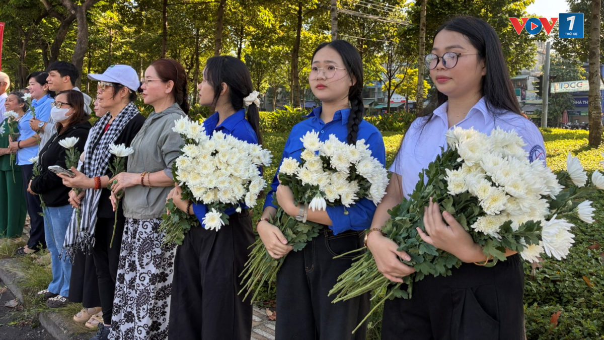 Tình nguyện viên ôm bông cúc trắng để phát cho người dân ven đường (Ảnh: Kim Dung)